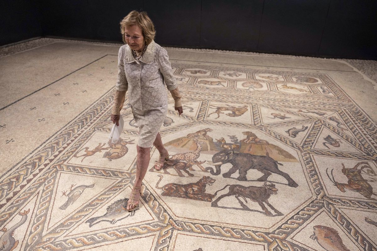US philantropist Shelby White poses for a picture on the roughly 1,700-year-old Lod mosaic, ahead of the inauguration of a new visitors centre she helped fund to display the prized piece in the mixed city of Lod in the centre of Israel, on June 27, 2022. - The Lod Mosaic Archaeological Center was specifically built to house the Roman mosaic dating back to the 3rd or 4th century CE, which was unearthed in the city in 1996 and described as "one of the most beautiful in the world". (Photo by MENAHEM KAHANA / AFP)