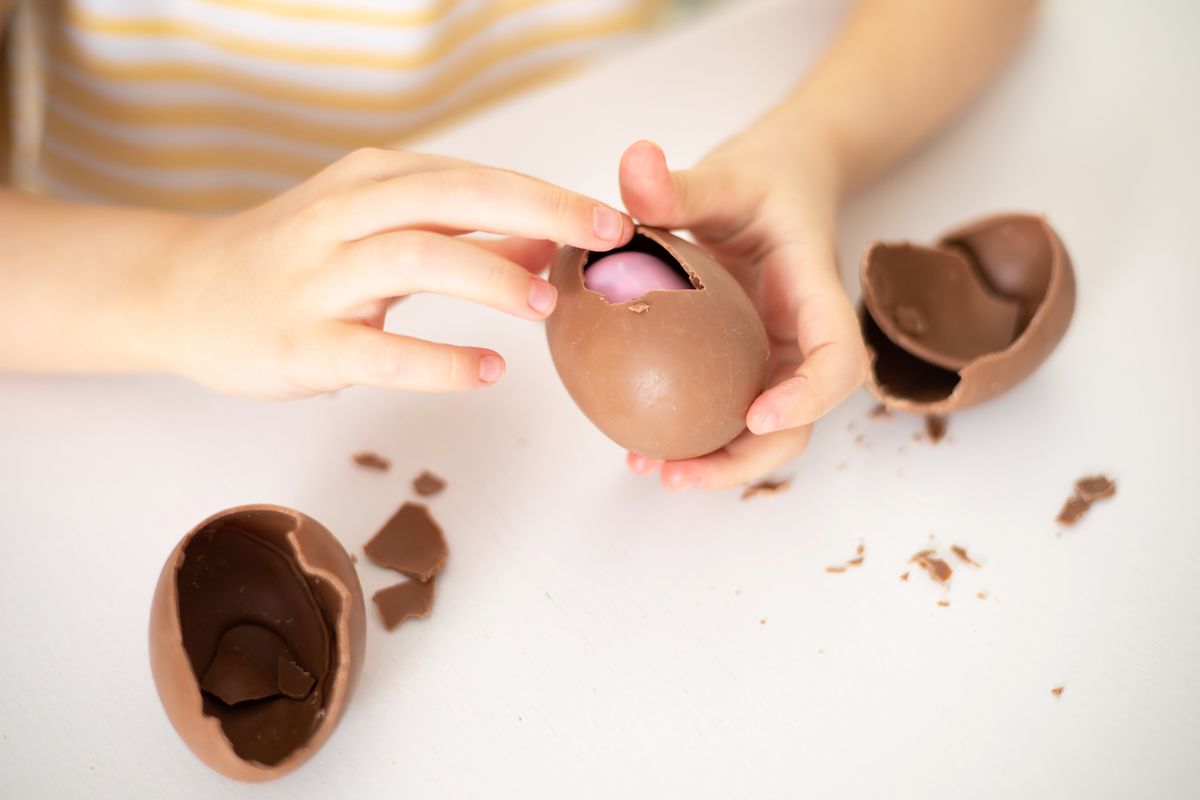 Happy,Easter.,Close-up,Of,Children's,Hands,Open,Breaking,Chocolate,Egg