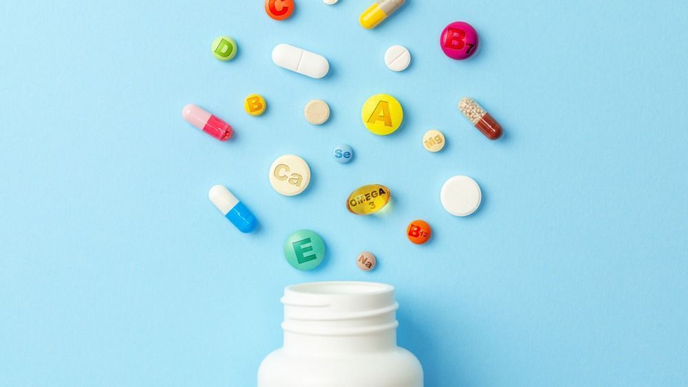 Vitamin,Tablets.,Bottle,With,Colored,Pills,On,Blue,Background.,Multivitamins.