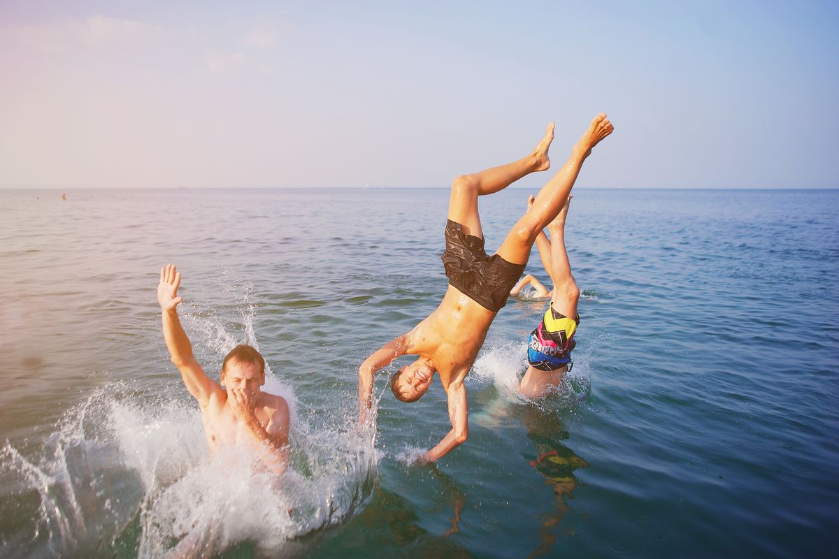 Young,People,Jumping,Inside,Ocean,In,Summer,Excursion,Day.,Happy