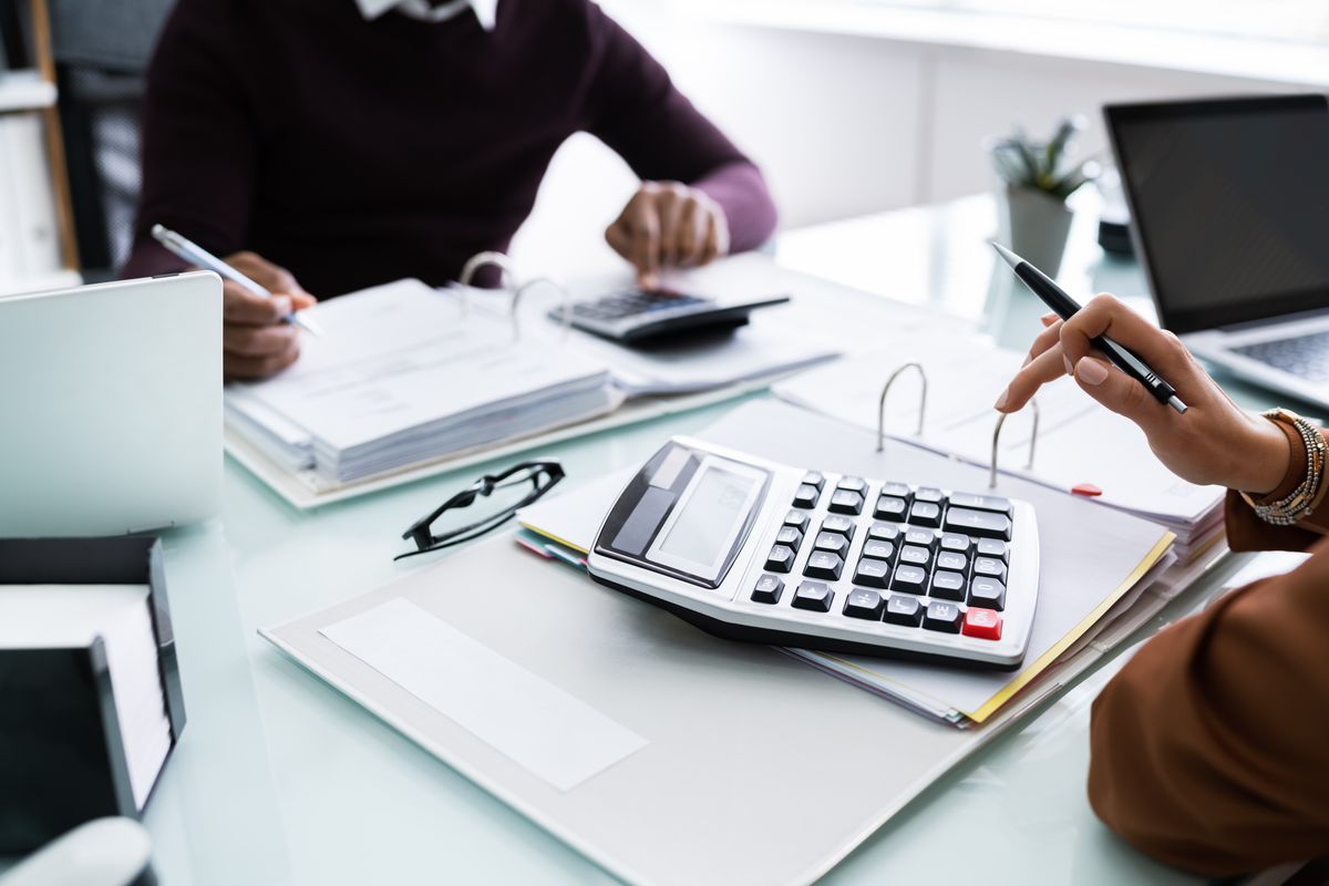 Close-up,Of,Two,Businesspeople,Calculating,Financial,Statement,At,Desk