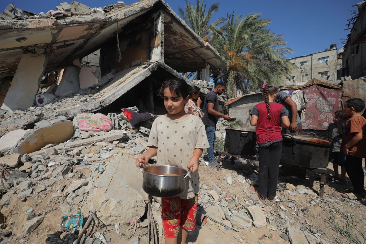 Palestinians in Gaza wait in line for hot meals