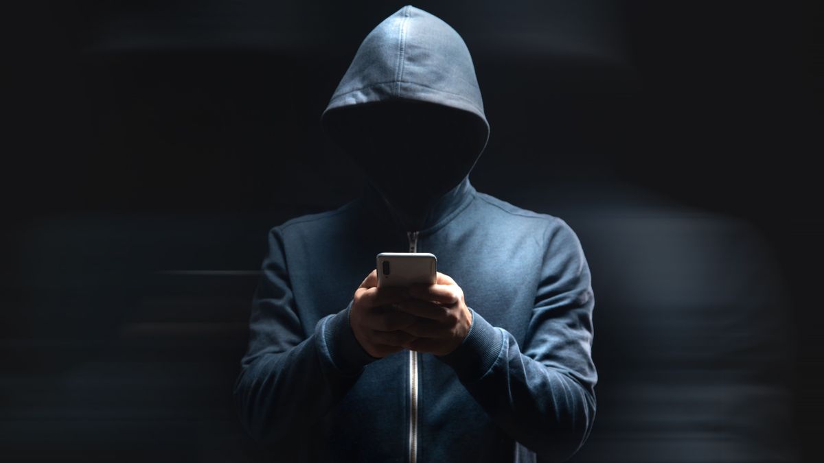 Holds,The,Phone,On,A,Dark,Background.,Hacker,Concept