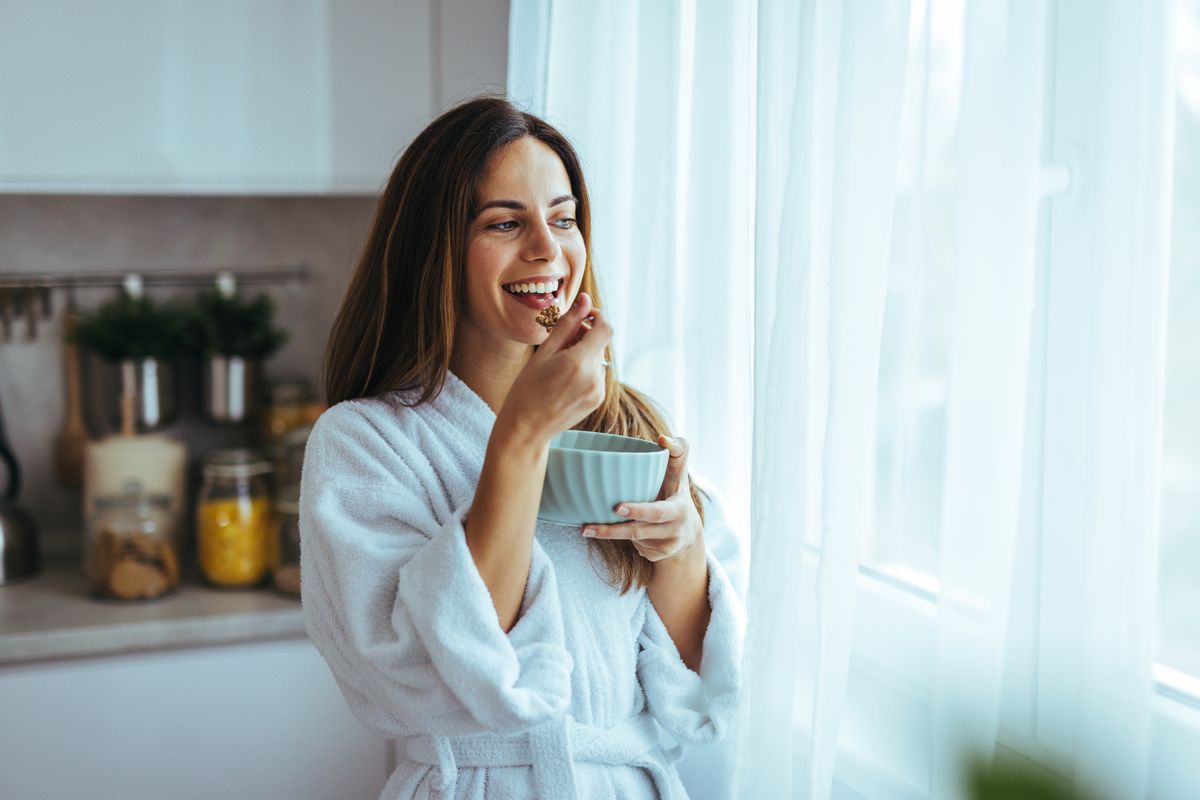 A,Joyful,Woman,In,A,Bathrobe,Enjoys,A,Healthy,Breakfast