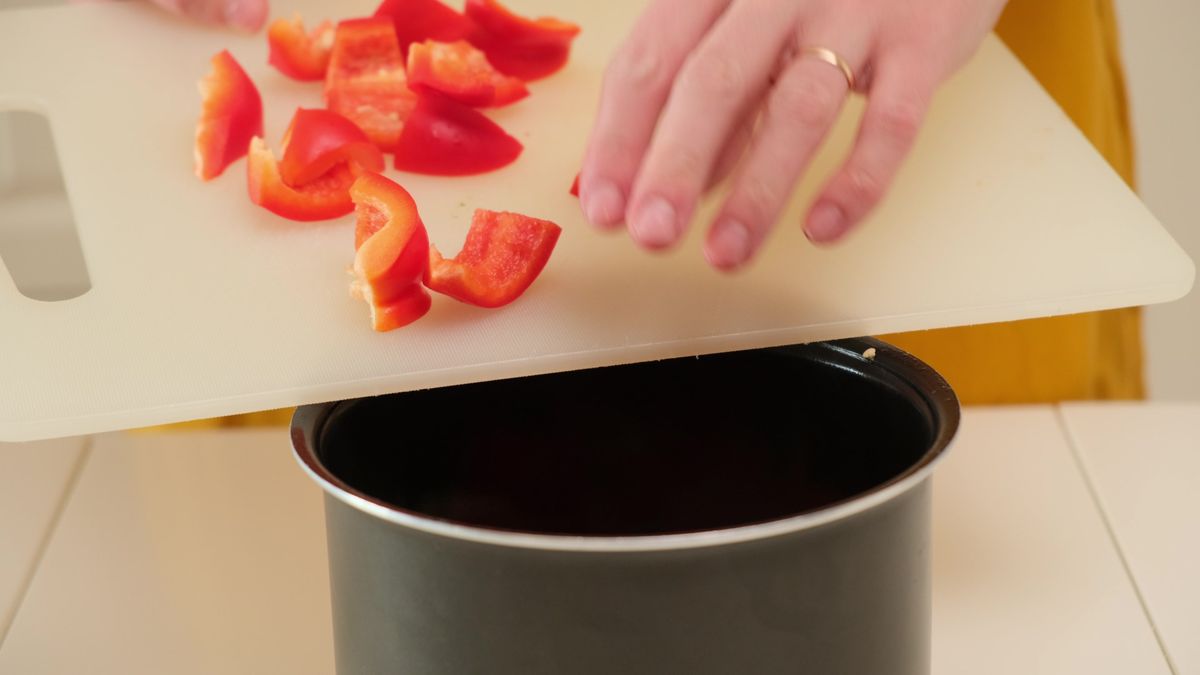 Chopped,Red,Bell,Pepper,On,Plastic,Cutting,Board,Being,Added